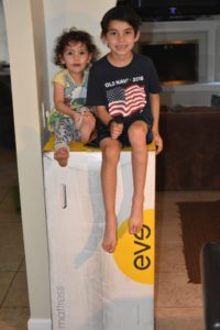 kids sitting on an eve mattress box